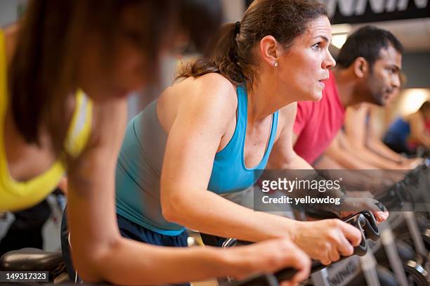 people using spin machines in gym - cours de spinning photos et images de collection