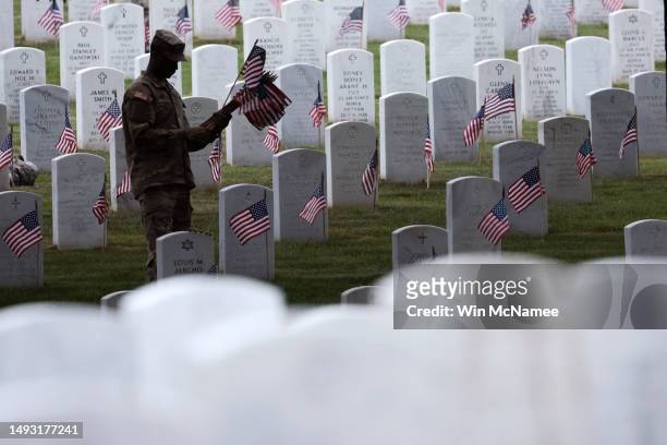 Members of the 3rd U.S. Infantry Regiment place flags at the headstones of U.S. Military personnel buried at Arlington National Cemetery, in...