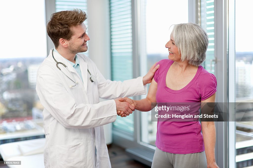 Doctor shaking womans hand in office