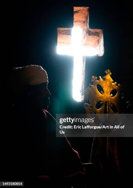 Ethiopian orthodox priest holding a cross inside a rock-hewn church, Amhara Region, Lalibela, Ethiopia on May 1, 2023 in Lalibela, Ethiopia.