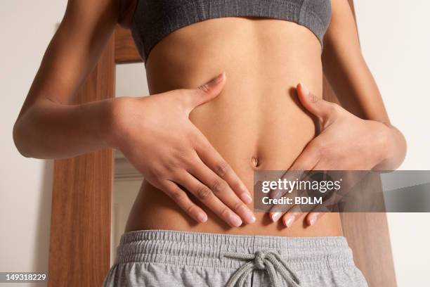 womans hands cupping her bellybutton - abdómen imagens e fotografias de stock