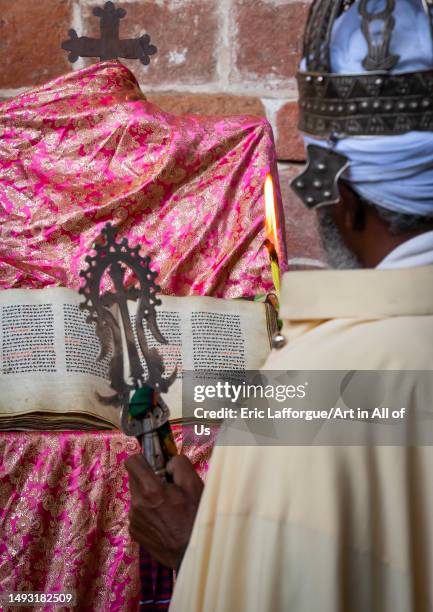 Ethiopian orthodox priest with an old bible in nakuto lab rock church, Amhara Region, Lalibela, Ethiopia on May 2, 2023 in Lalibela, Ethiopia.