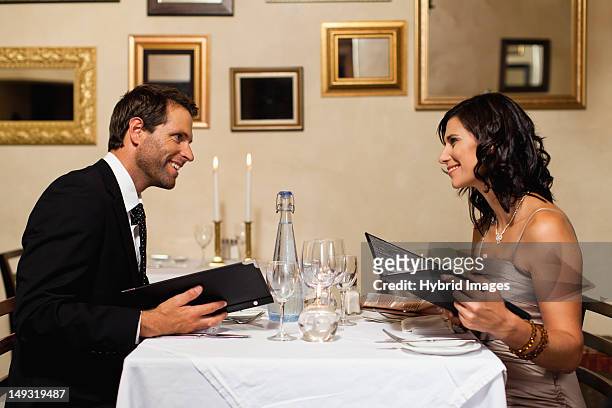 couple examining menus in restaurant - kerzenschein stock-fotos und bilder