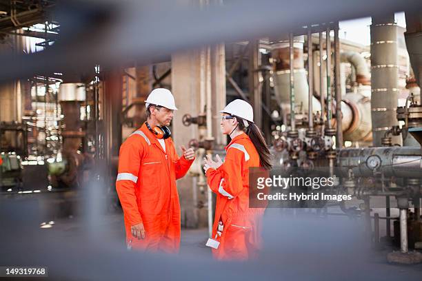 workers talking at oil refinery - olie industrie stockfoto's en -beelden
