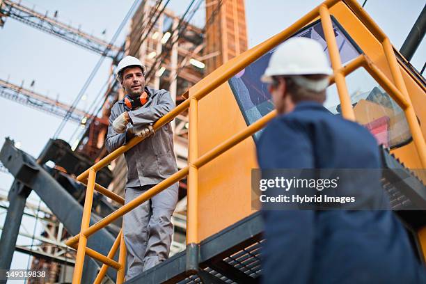 arbeiter sprechen in ölraffinerie - baumaschine stock-fotos und bilder