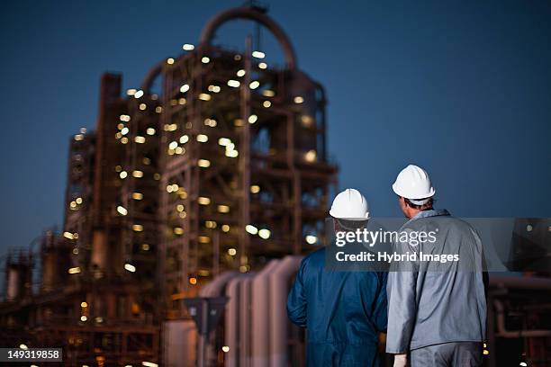 workers standing at oil refinery - white jumpsuit stock pictures, royalty-free photos & images