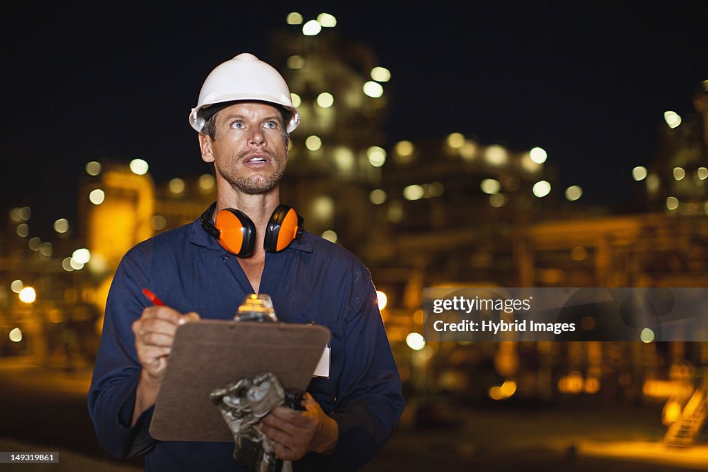 Worker with clipboard at oil refinery