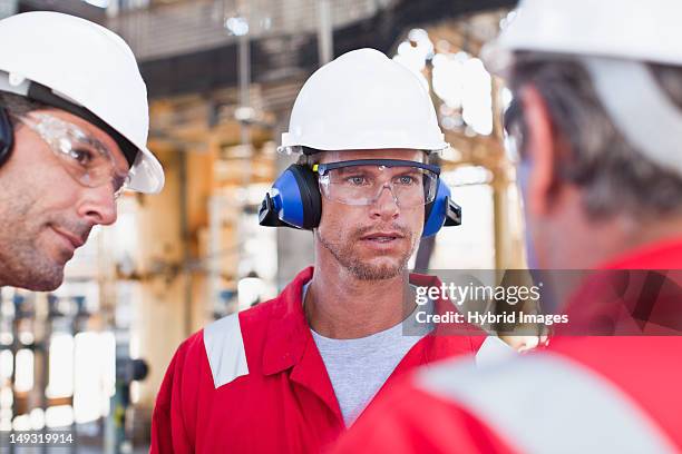 workers talking at oil refinery - ear protection stock pictures, royalty-free photos & images