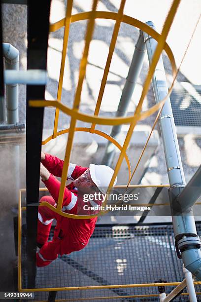 worker climbing ladder at oil refinery - oliewerker stockfoto's en -beelden