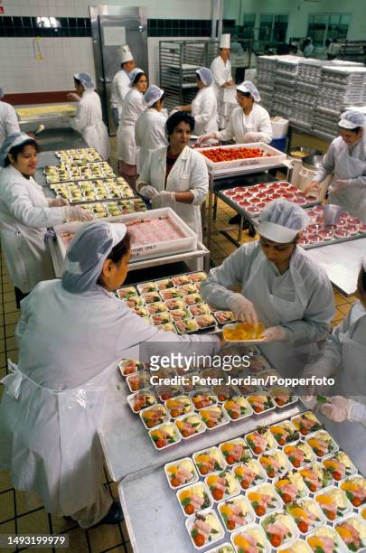 Catering staff prepare meals for Club Class airline passengers in a kitchen prep area at British Airways Catering Division's Heathrow Airport...