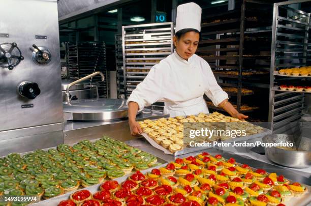 Member of catering staff prepares fruit tarts for consumption by airline passengers in a kitchen prep area at British Airways Catering Division's...