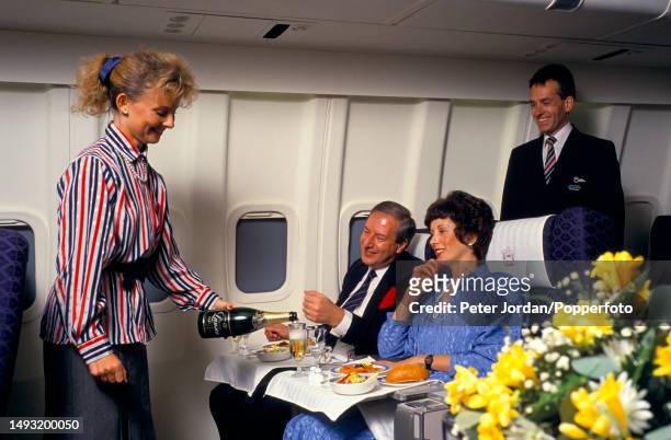 Two passengers are served a meal by cabin crew members in the mock up first class cabin of a British Airways aircraft at Heathrow Airport in west...
