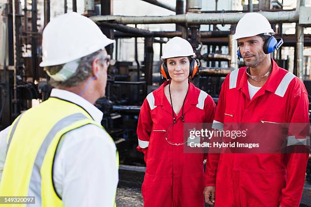 workers talking at chemical plant - oliewerker stockfoto's en -beelden