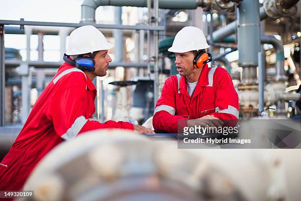 workers talking at chemical plant - oorbeschermer stockfoto's en -beelden