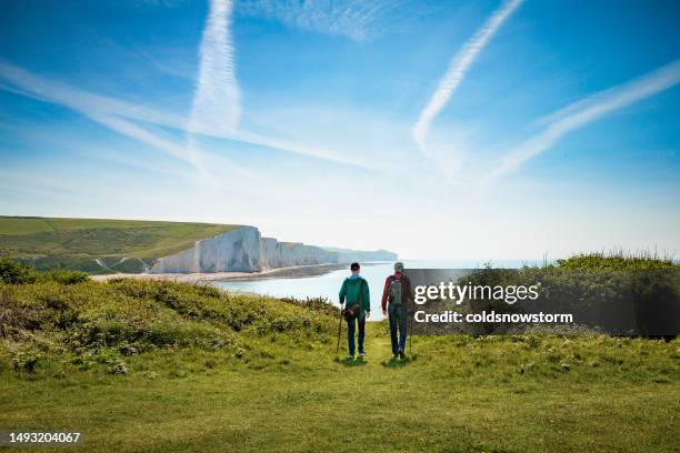 two friends hiking together at seven sisters cliffs on the english south coast - hiking stock pictures, royalty-free photos & images