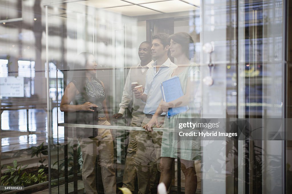 Business people riding glass elevator