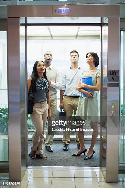 business people riding glass elevator - aufzug business stock-fotos und bilder