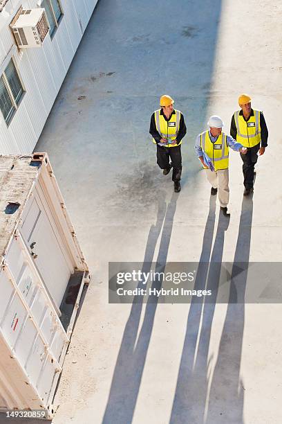 lavoratori fusione ombre sul sito - indumento fluorescente foto e immagini stock