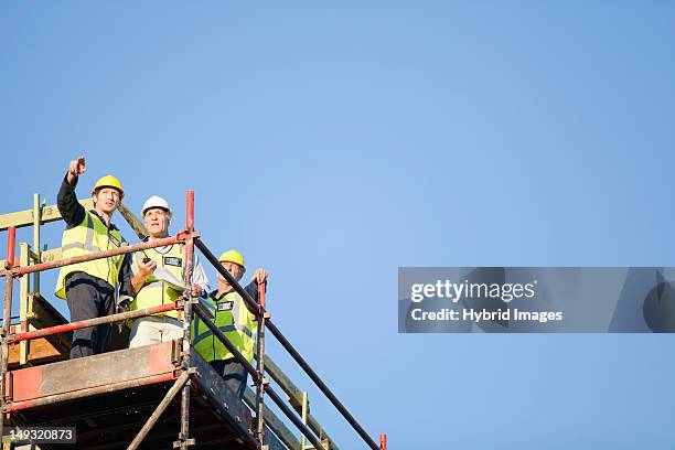 workers standing on scaffolding on site - railing stockfoto's en -beelden