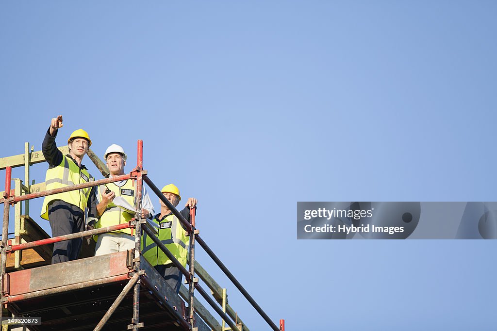 Workers standing on scaffolding on site