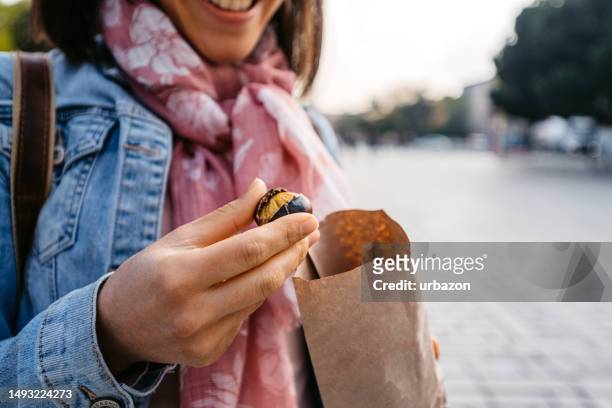 junge frau isst geröstete kastanien auf der straße in istanbul - maroni stock-fotos und bilder