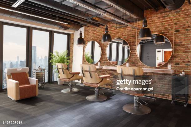 interior de la peluquería con sillas, espejos, luces colgantes, pared de ladrillo y paisaje urbano desde la ventana - barbero peluquería fotografías e imágenes de stock