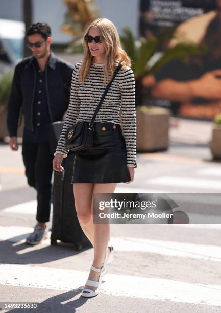 Stacy Martin is seen wearing a black and white stripped fluffy shirt, black mini leather skirt with golden statements, white sandals heels, black...