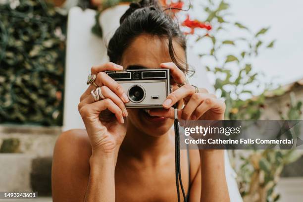 a woman takes a photo with an old film camera - gifted movie stock-fotos und bilder