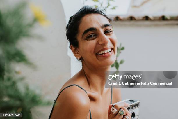 simple low angle portrait of a young indian woman looking at the camera. - looking over his shoulder stockfoto's en -beelden