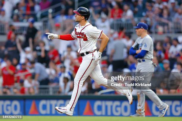 Matt Olson of the Atlanta Braves reacts as he rounds first after hitting a solo home run while Freddie Freeman of the Los Angeles Dodgers looks on...