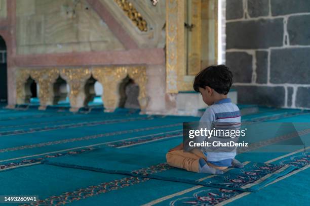 boy sitting in the mosque praying with open hands. - moské bildbanksfoton och bilder