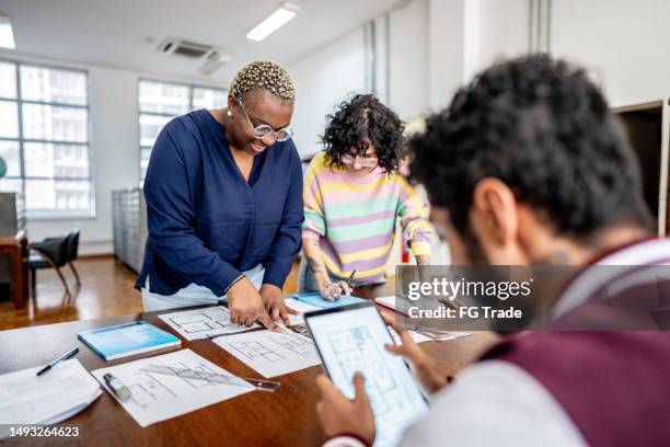 kolleginnen und kollegen im gespräch in einer besprechung in der bibliothek - bauingenieurwesen stock-fotos und bilder