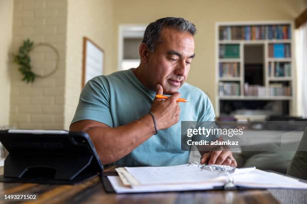 hombre maduro trabajando desde casa usando una computadora - hacienda fotografías e imágenes de stock