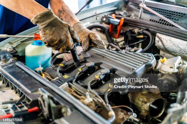 professional mechanic working on the engine of the car in the garage - racing garage stock pictures, royalty-free photos & images