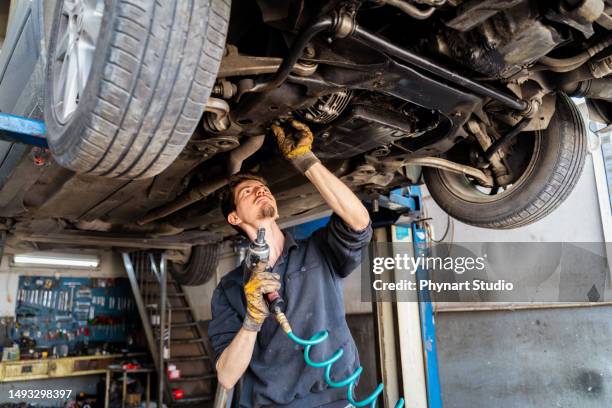 young man car mechanic in auto repair shop - car mechanic stockfoto's en -beelden