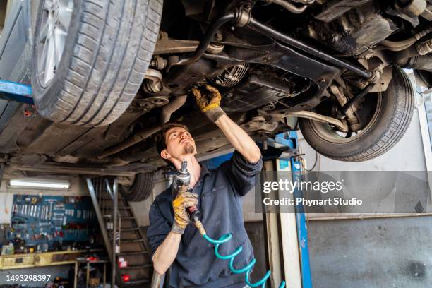 young man car mechanic in auto repair shop - auto mechanic stock pictures, royalty-free photos & images