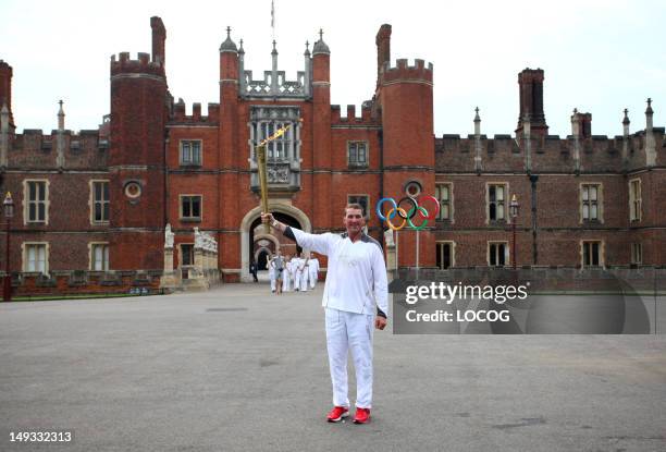 In this handout image provided by LOCOG, Olympic Gold Medalist rower Torchbearer 011 Matthew Pinsent stands in front of the Great Gate at Hampton...