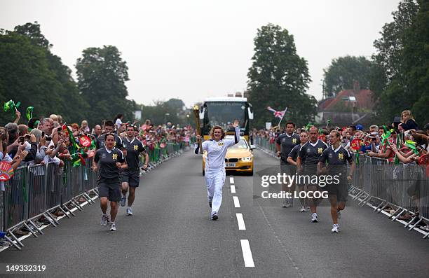 In this handout image provided by LOCOG, Torchbearer 001 Rosie Hynes carries the Olympic Flame on the Torch Relay leg between Bushy Park and Hampton...