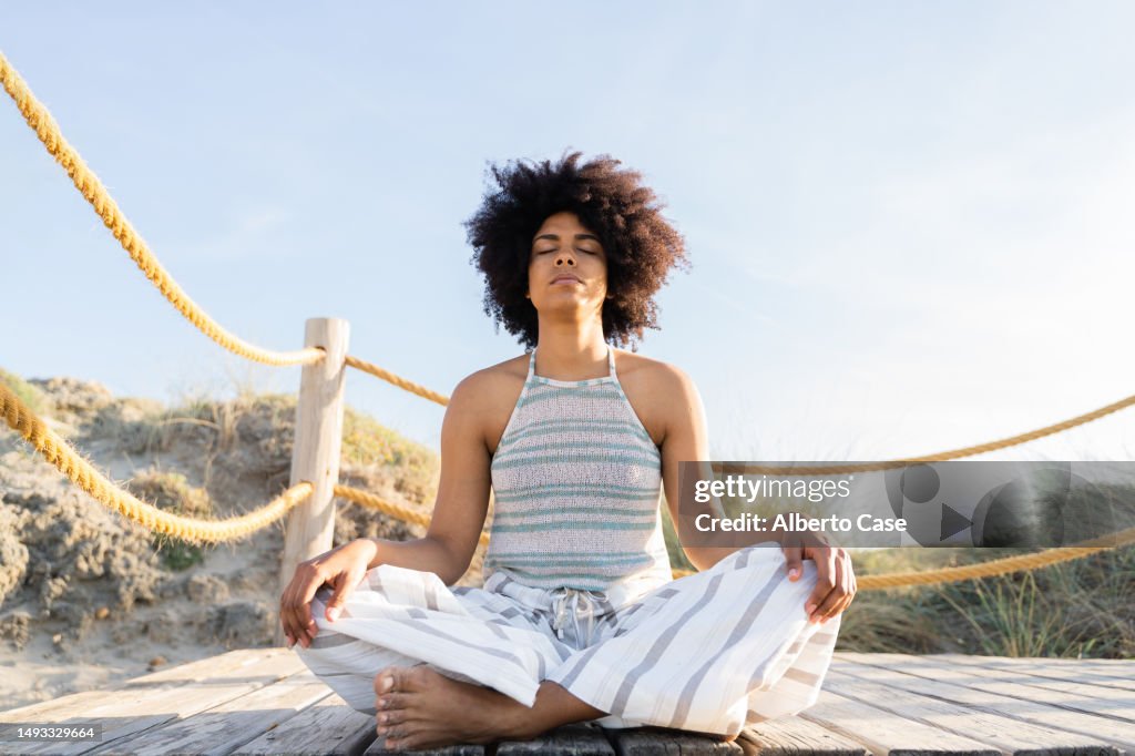A woman meditating at sunset