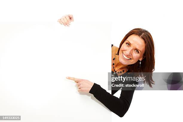 mujer madura aislado sobre fondo blanco mirando a placa - mirar alrededor fotografías e imágenes de stock