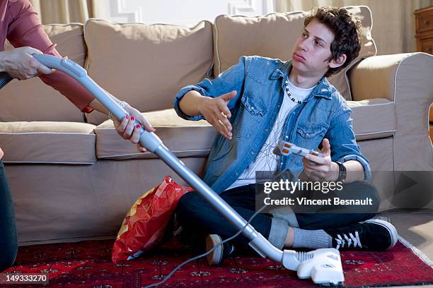 a boy's gaming interrupted by his mum's vacuuming - aergerlich stock-fotos und bilder