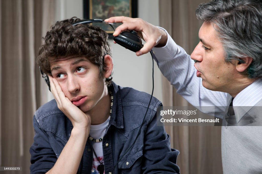 A teen with headphones being told off by his dad