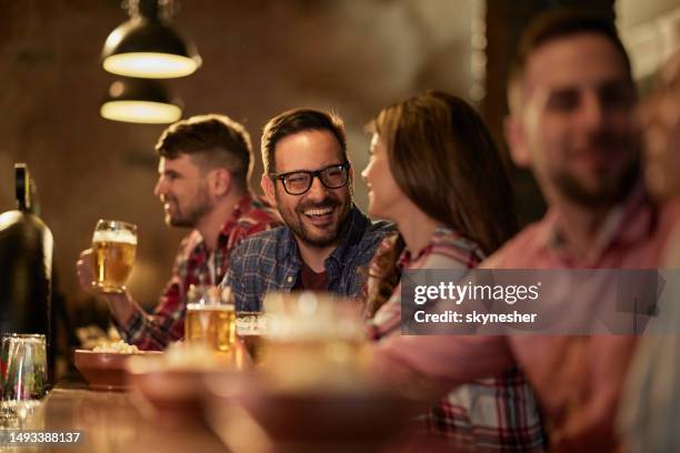 jeune couple heureux parlant tout en buvant de la bière dans un pub. - bar photos et images de collection