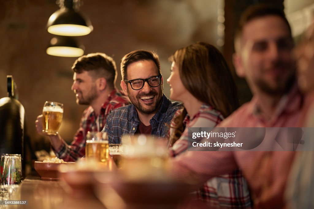 Young happy couple talking while drinking beer in a pub.
