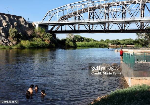 People cool off in the long-depleted Colorado River, currently swollen by winter snowmelt water, as it flows on May 25, 2023 in Yuma, Arizona. States...