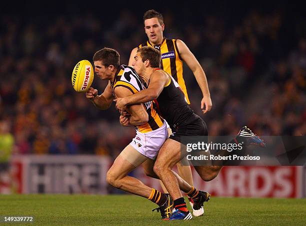 Ben Stratton of the Hawks handballs under pressure during the round 18 AFL match between the Essendon Bombers and the Hawthorn Hawks at Etihad...