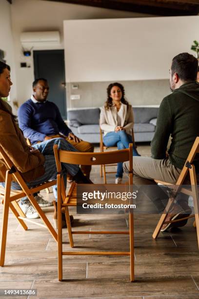 group of people sitting in circle, talking during group therapy - rehabilitation meeting stock pictures, royalty-free photos & images