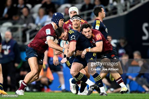 Freddie Burns of the Highlanders is met by the defence during the round 14 Super Rugby Pacific match between Highlanders and Queensland Reds at...