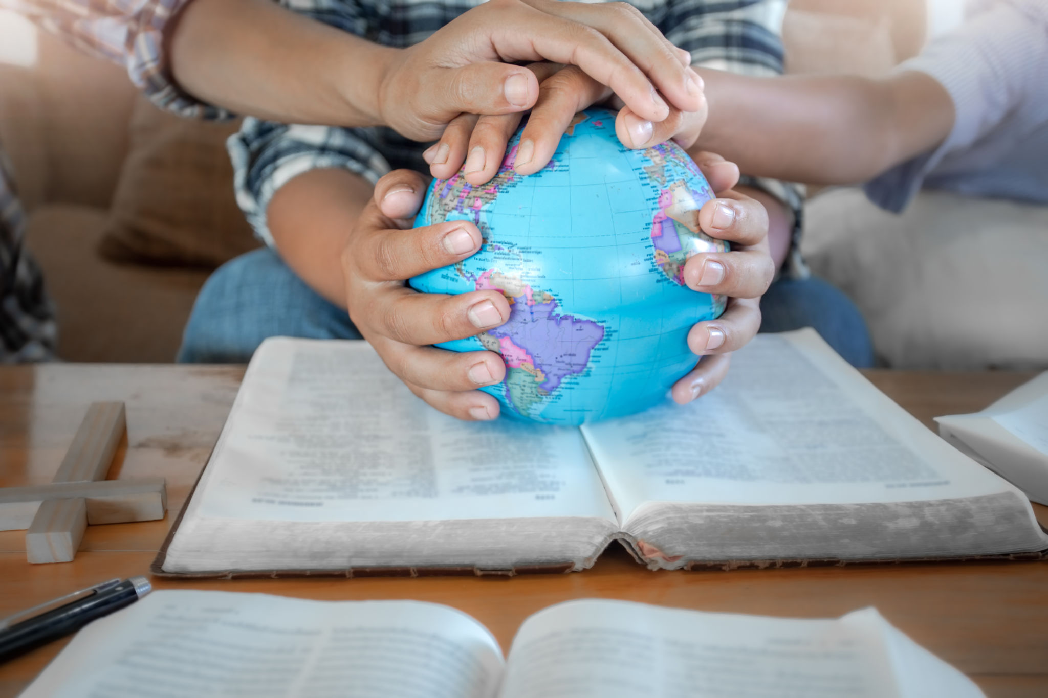 Close up hands of christian group praying for globe and people around the world on wooden table with bible. Close up hands of christian group praying for globe and people around the world on wooden table with bible.