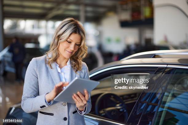 smiling saleswoman using touchpad in a car showroom. - touchpad stock pictures, royalty-free photos & images